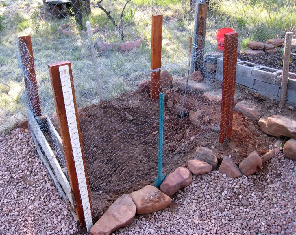 A small vegetable garden enclosed by a homemade wire fence