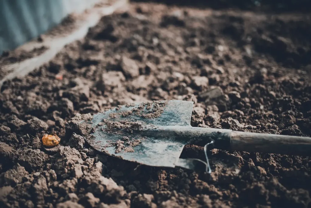 A garden tool resting on freshly prepared soil before planting